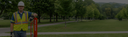 Person in safety gear standing next to a pole in a park-like setting